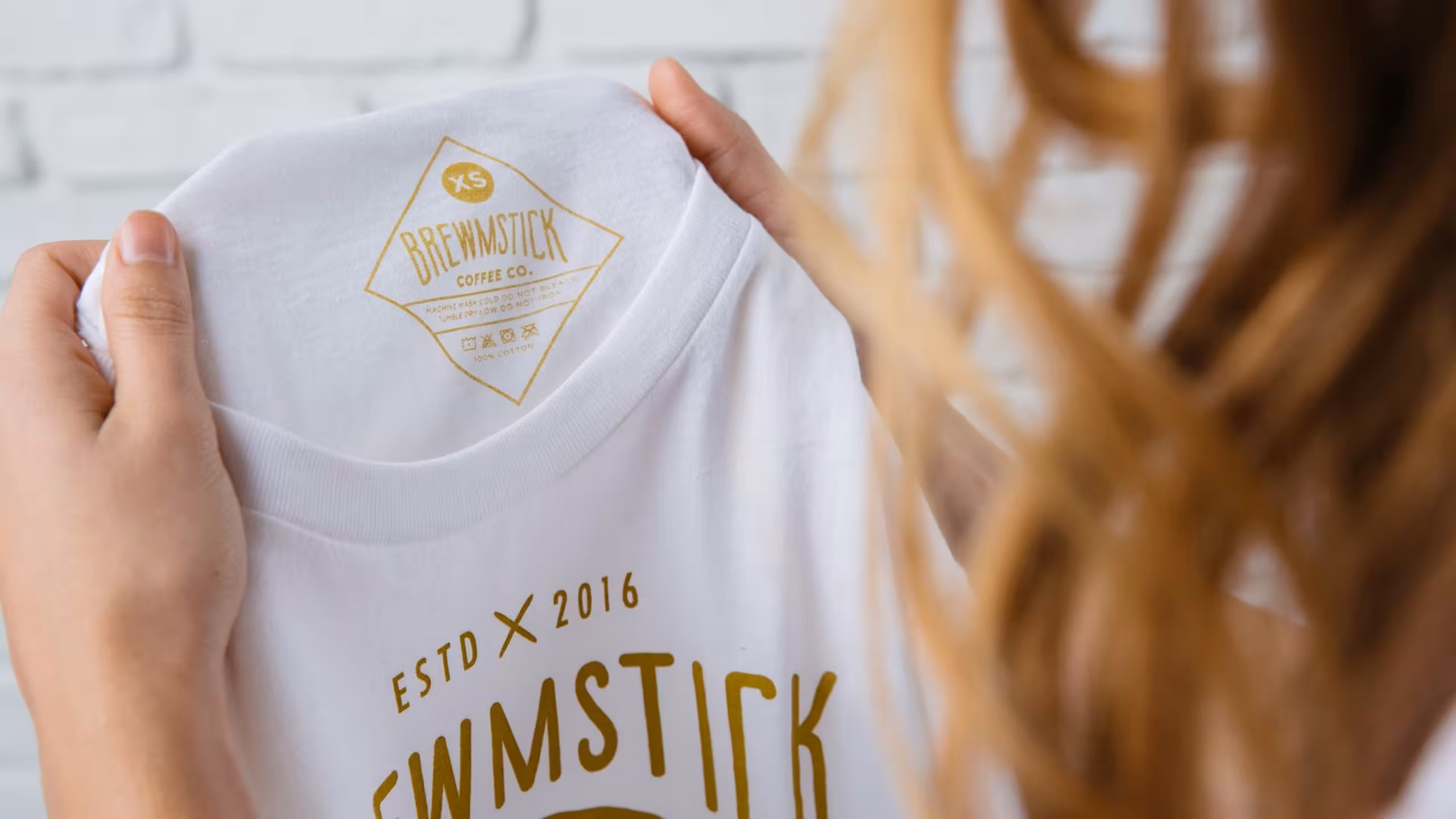 girl holding up white shirt with hold tag print