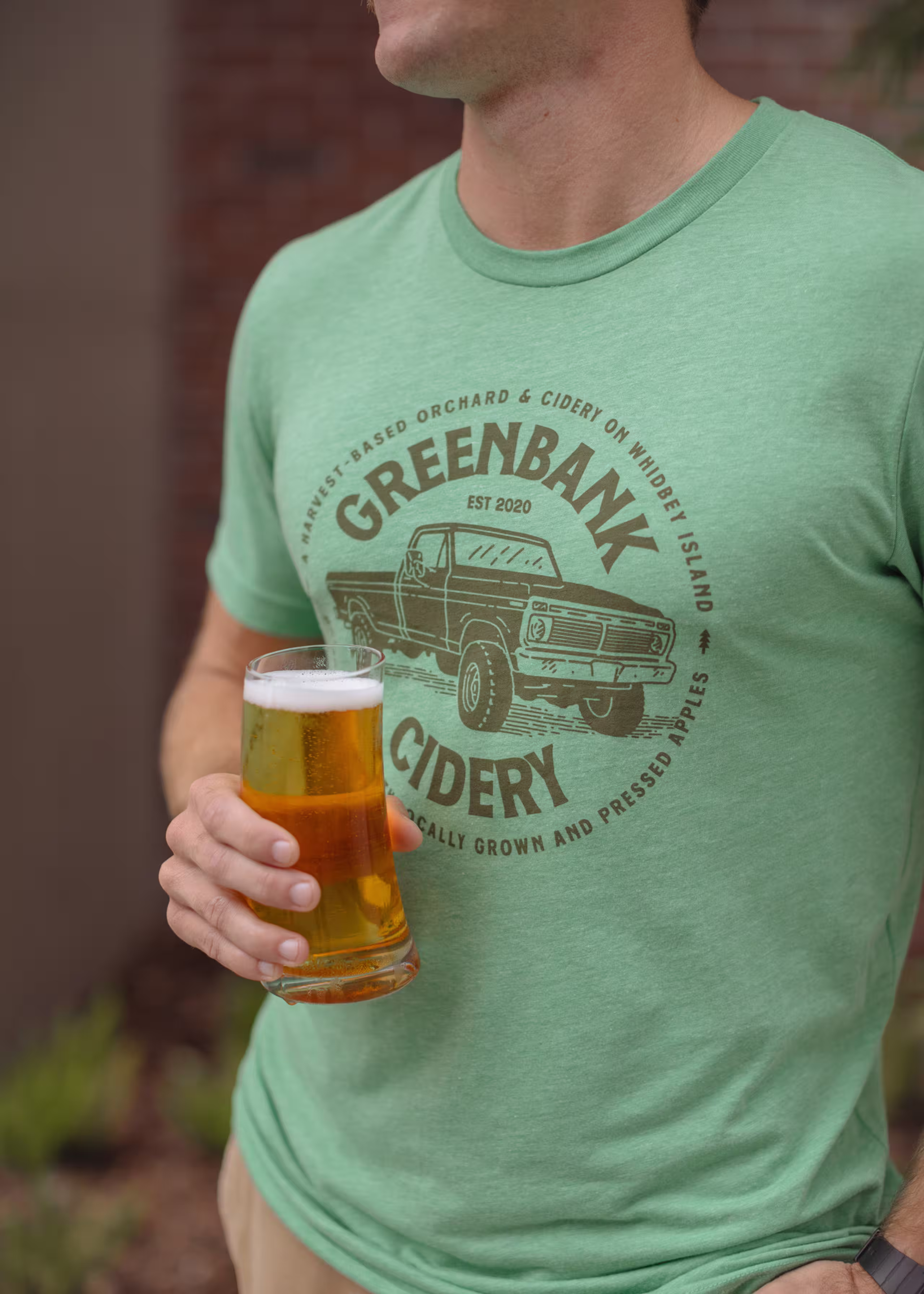 man wearing a green shirt holding a filled glass