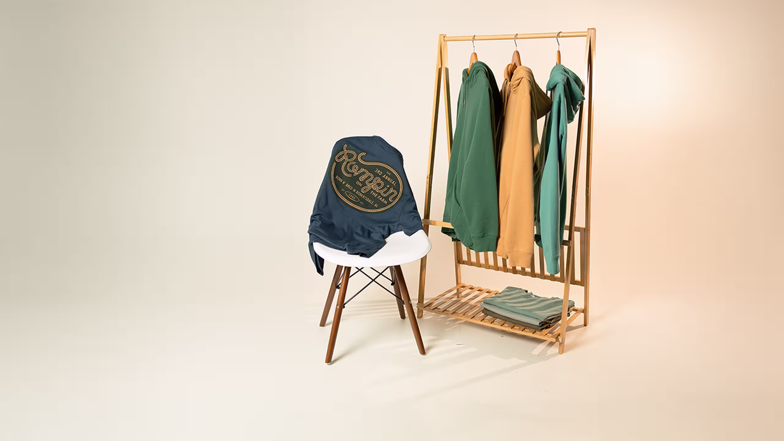 t-shirt over a white chair and hoodies hanging on a wood rack