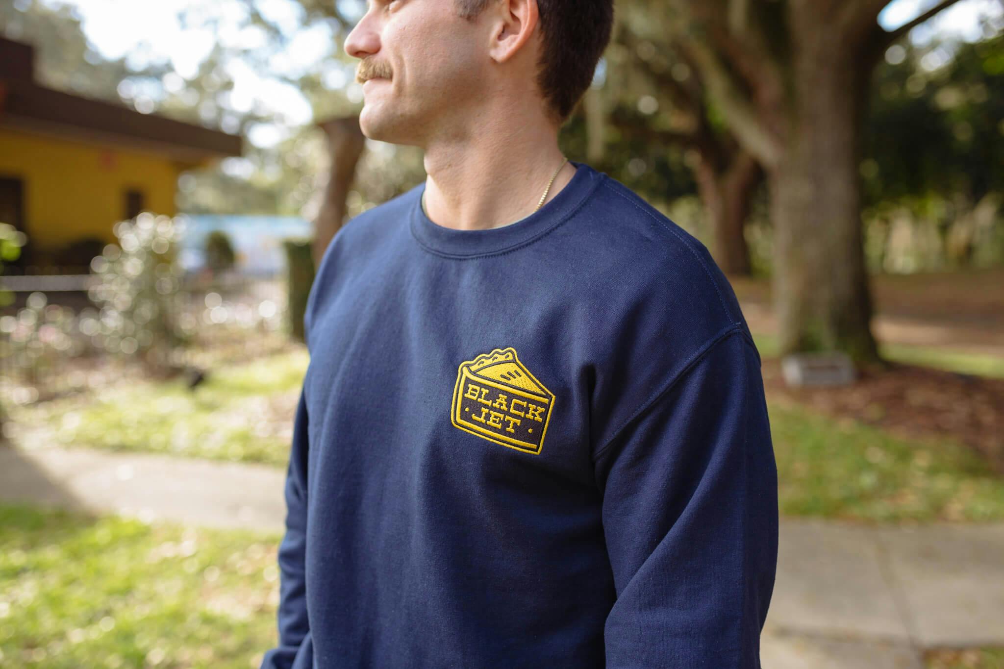 a man wears a custom crewneck sweatshirt with a patch on it a man wears a custom crewneck sweatshirt with a patch on it